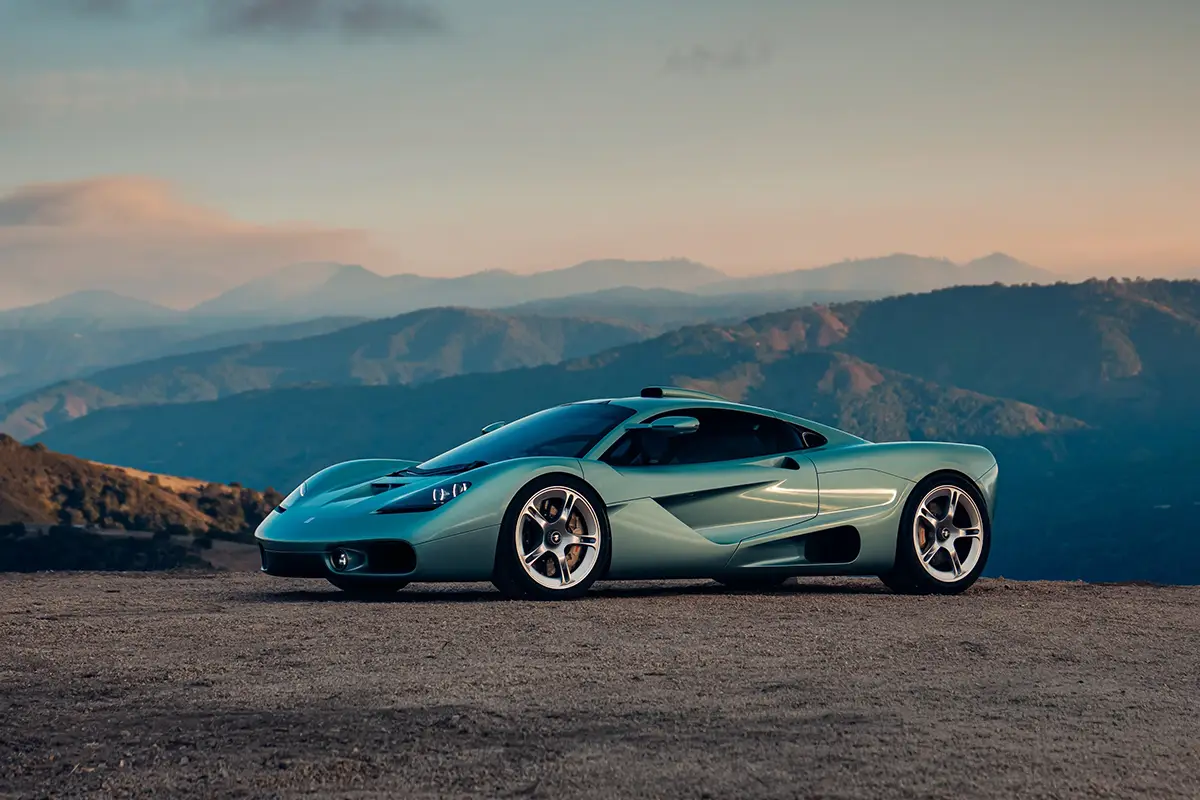 Seitenansicht des flachen Gordon Murray S1 Supersportwagens in Hellgrün vor einer Berglandschaft im Abendlicht.
