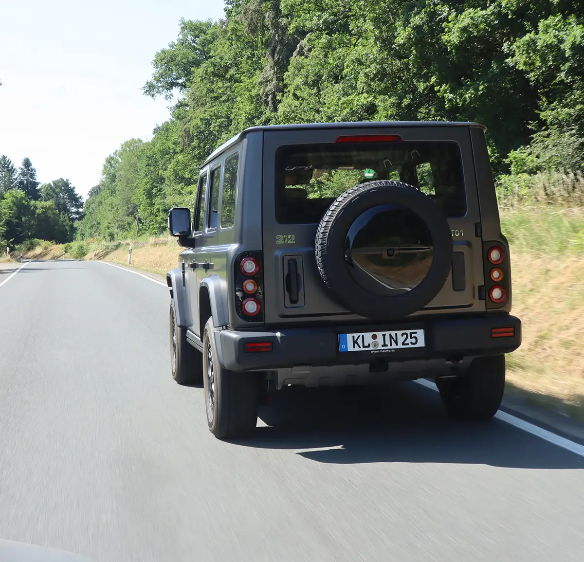 Heckansicht des grauen BAW 212 auf einer Strasse mit dem aussen am Heck montierten Ersatzrad und robusten Stossfängern.