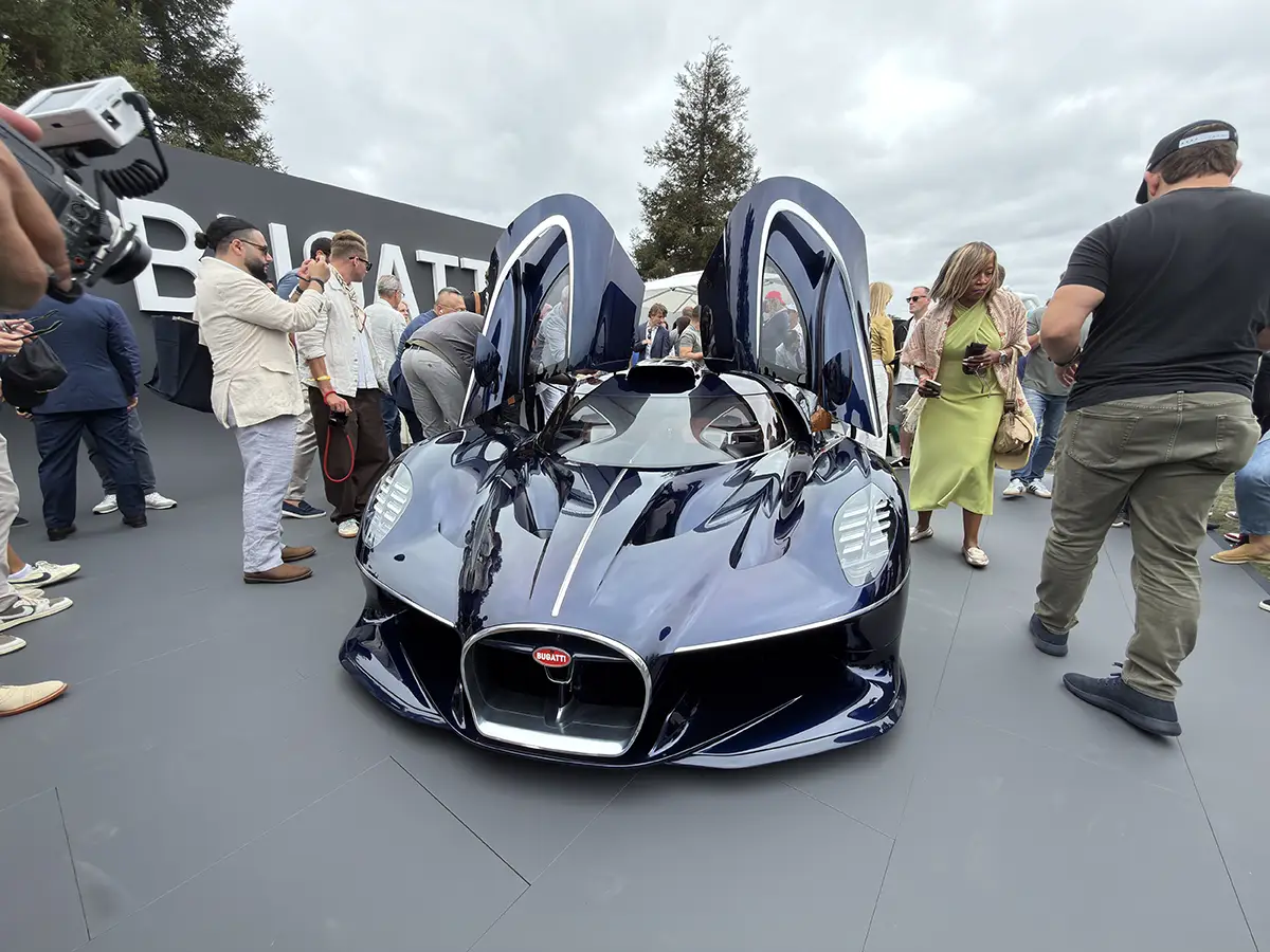 Der dunkelblaue Bugatti Destrier mit weit nach oben öffnenden Schmetterlingstüren umringt von Messebesuchern.