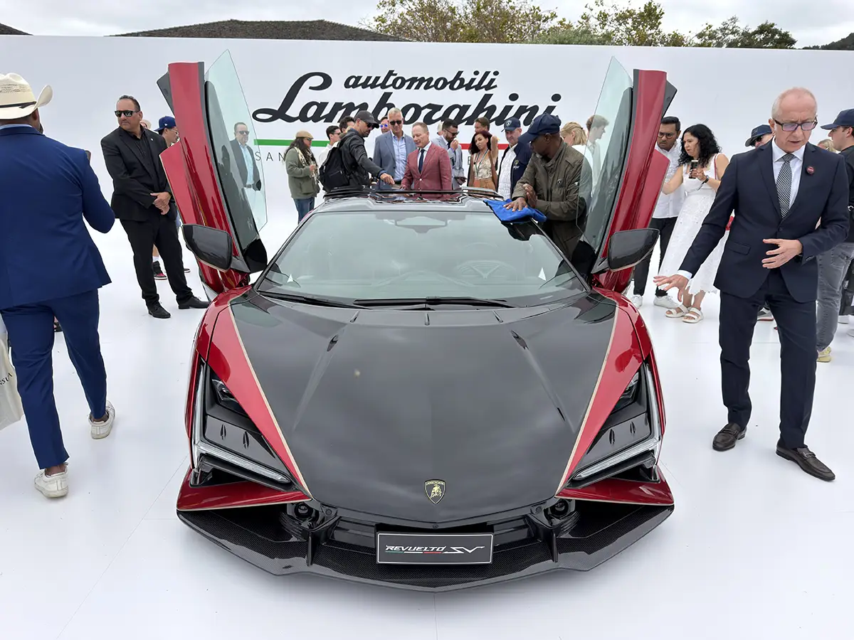 Frontalansicht des roten Lamborghini Revuelto SV mit geöffneten Scherentüren und Carbonhaube bei der Präsentation auf The Quail.
