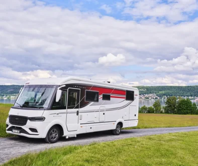 Kabe Imperial Ri830 Traq 4x4 vollintegriertes Allrad-Luxuswohnmobil auf Mercedes Sprinter auf einer Asphaltstrasse vor grüner Hügellandschaft.