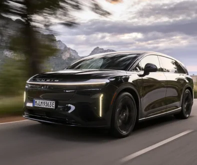 Ein tiefschwarzer Lucid Gravity Grand Touring in der Farbe Abyss Black fährt dynamisch auf einer asphaltierten Bergstrasse vor einer Hügelkulisse.