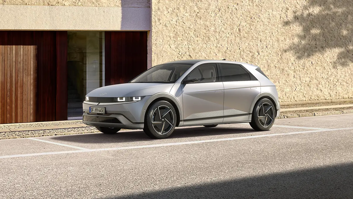 Silberner Hyundai Ioniq 5 im kantigen Retro-Design auf einem Parkplatz vor einem modernen Gebäude.