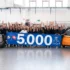 Die gesamte Belegschaft des AMFI-Werks in Turin jubelt mit erhobenen Händen hinter einem 5'000-Banner neben dem bronzenen Jubiläums-Microlino. Foto: Microlino