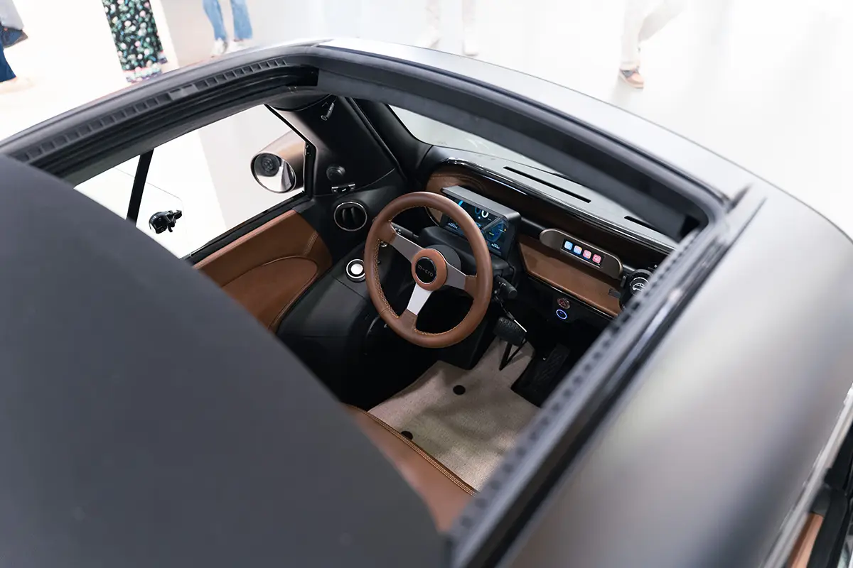 Blick von oben durch das geöffnete Schiebedach in das braune Leder-Cockpit des massgeschneiderten 5'000sten Microlino.