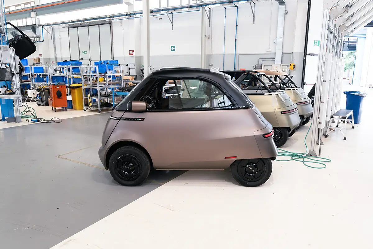 Seitenansicht des bronzenen Microlino Jubiläumsmodells mit schwarzen Alufelgen auf der Endmontage-Linie bei AMFI. Foto: Microlino