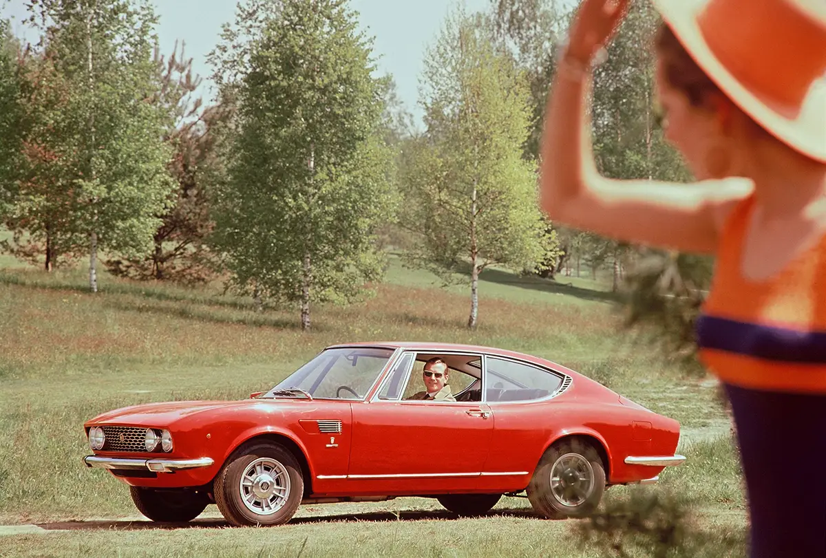 Rotes Fiat Dino Coupé von Bertone auf einem sonnigen Waldweg