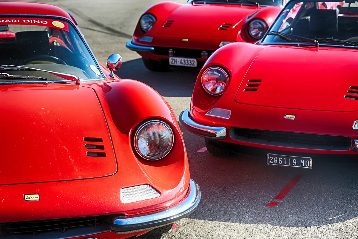 Drei rote Dino 206 GT und 246 GT Sportwagen mit geschwungenen Kotflügeln in Reihe geparkt