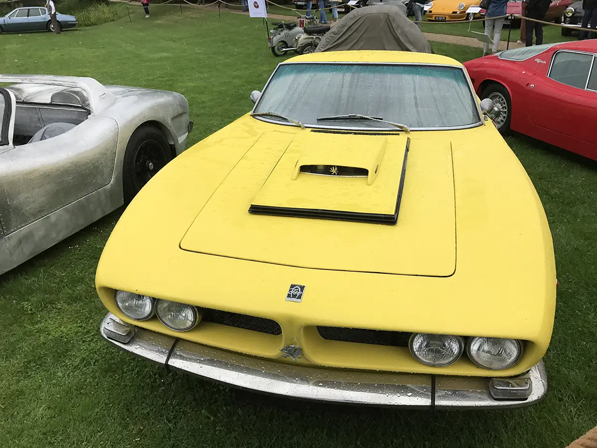 Gelber De Tomaso Mangusta Sportwagen mit Lufthutze auf der Motorhaube auf einer Wiese