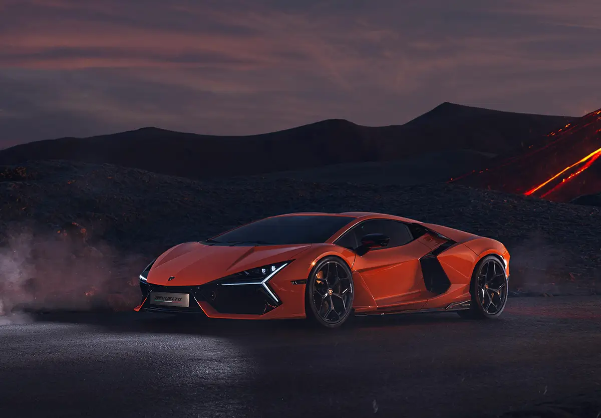 Orangener Lamborghini Revuelto Plug-in-Hybrid-Supersportwagen mit V12-Motor vor Bergkulisse in der Dämmerung