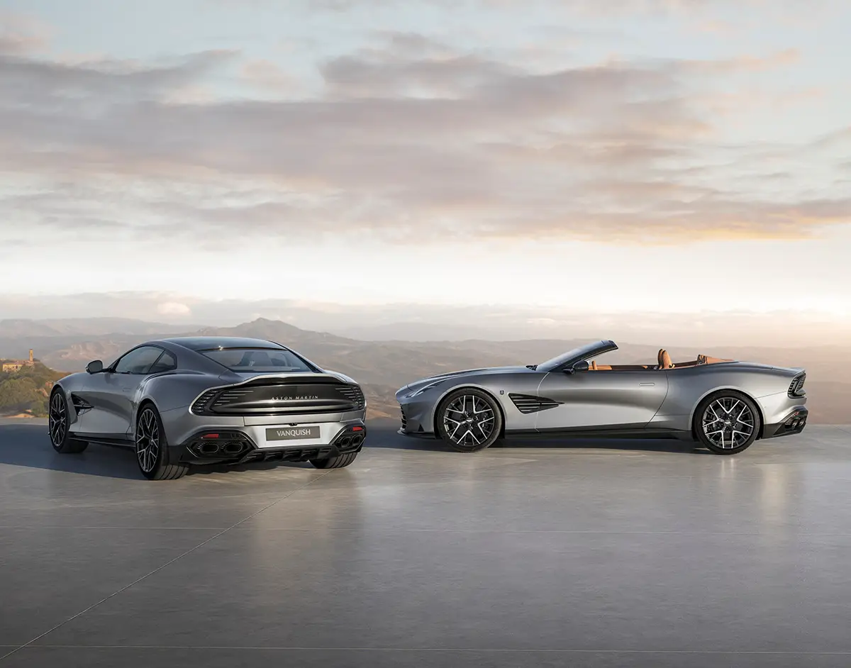Aston Martin Vanquish V12 Coupé und Volante Cabriolet im Profil vor dunstiger Landschaft