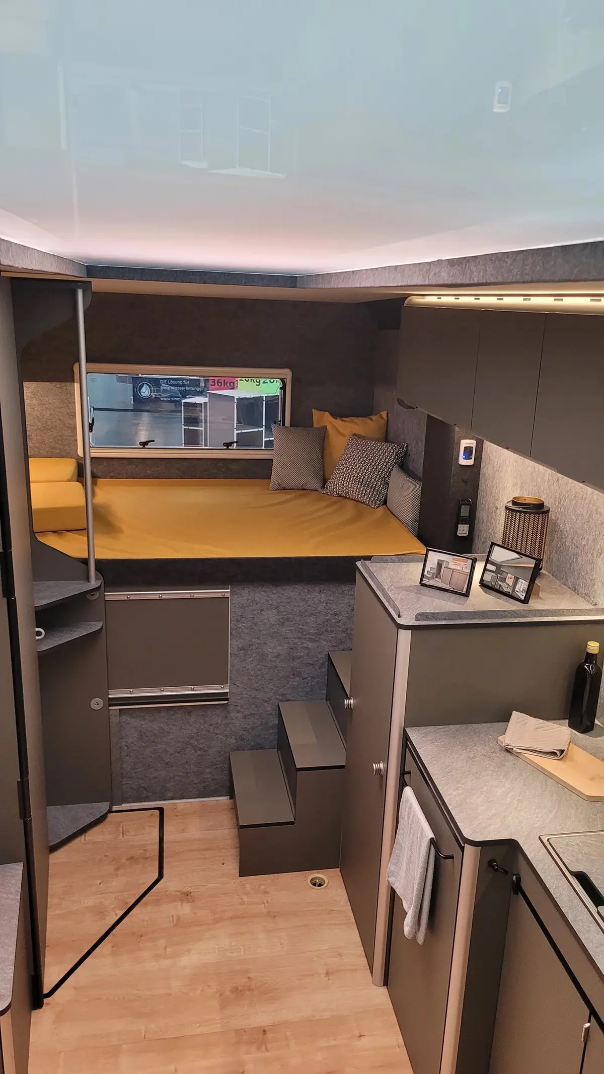 Blick auf das erhöhte Heck-Querbett mit integrierten Treppenstufen und Kleiderschrank im Innenraum des CityFreighter Evolve.