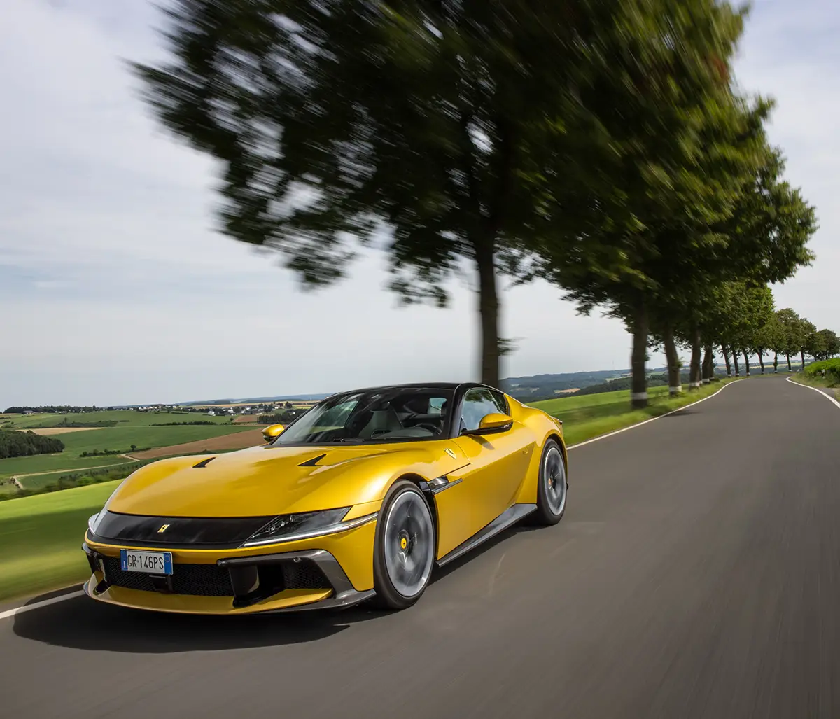 Gelber Ferrari 12Cilindri mit 830-PS-V12-Saugmotor in zügiger Fahrt auf einer Alleenstraße