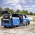 Zweifarbiger blau-weisser VW ID.California Cruise Elektro-Camper mit geöffneter Heckklappe und Campingmöbeln in den Dünen.