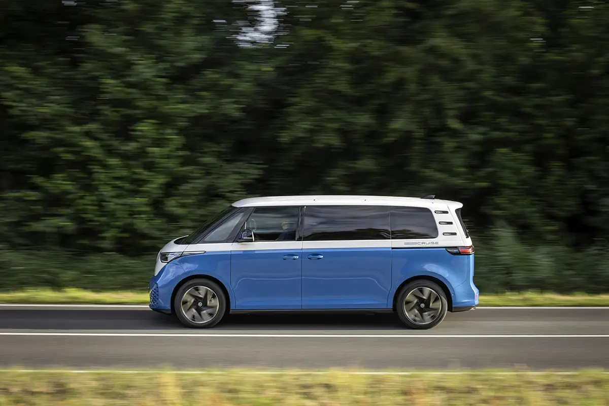 Zweifarbiger VW ID.Buzz mit langem Radstand bei dynamischer Fahrt auf einer Landstrasse.