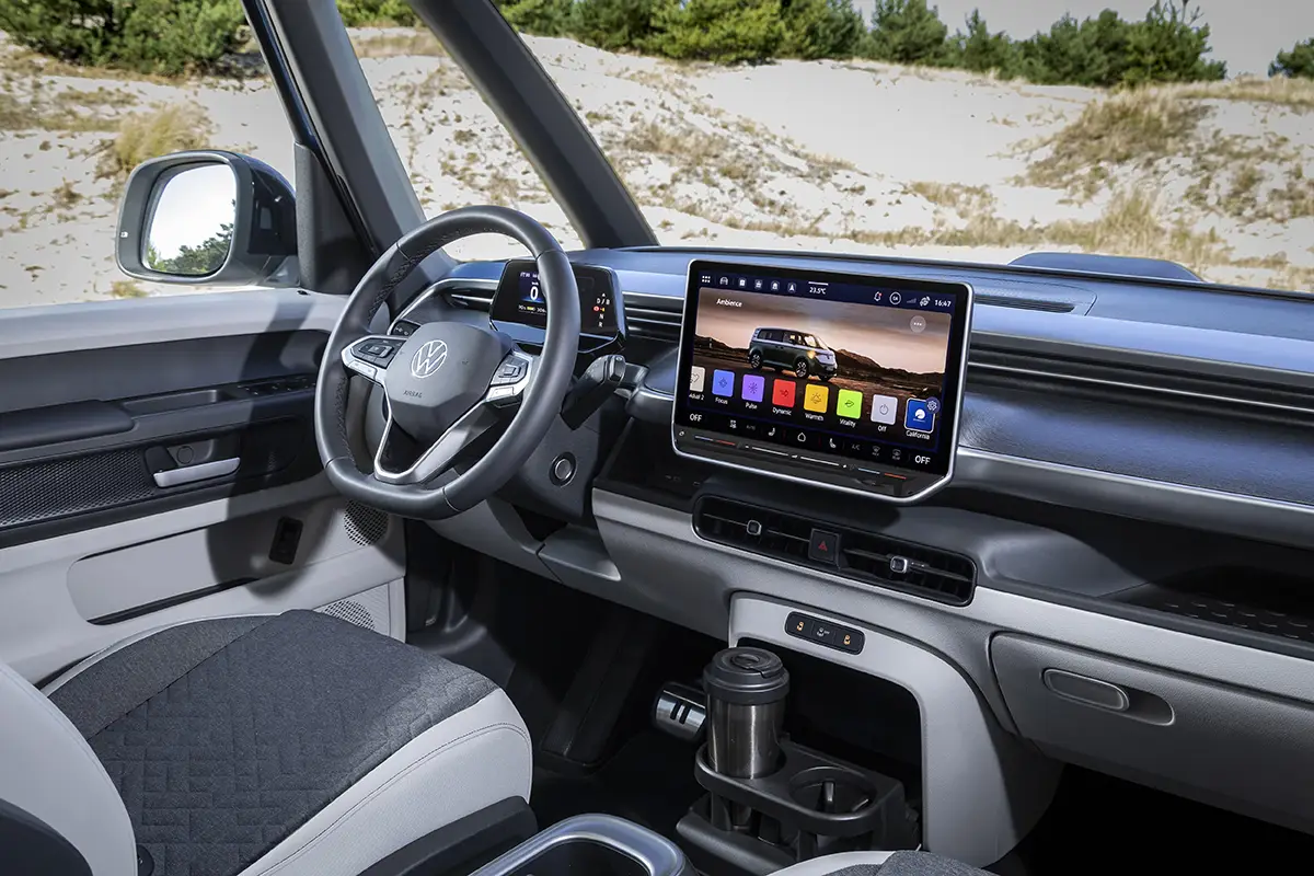 Modernes Cockpit des VW ID.California Cruise mit grossem Infotainment-Touchscreen und geöffnetem California-Camping-Menü.