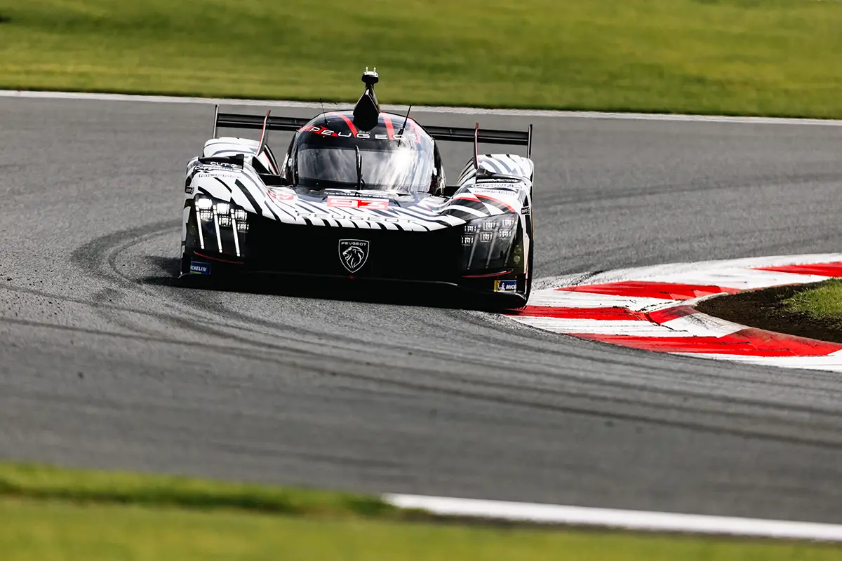 Der PEUGEOT 9X8 in Schwarz-Weiß-Zebra-Optik dynamisch in einer schnellen Kurvenkombination des Fuji Speedways. Foto: Peugeot Sport
