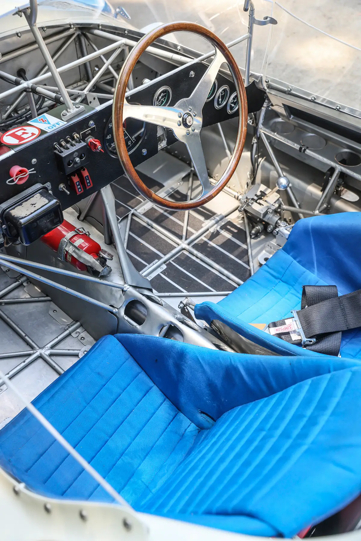Blick von oben in das Cockpit des Maserati Tipo 61 mit zwei blauen Schalensitzen, Holzlenkrad und sichtbarem Gitterrohrrahmen.