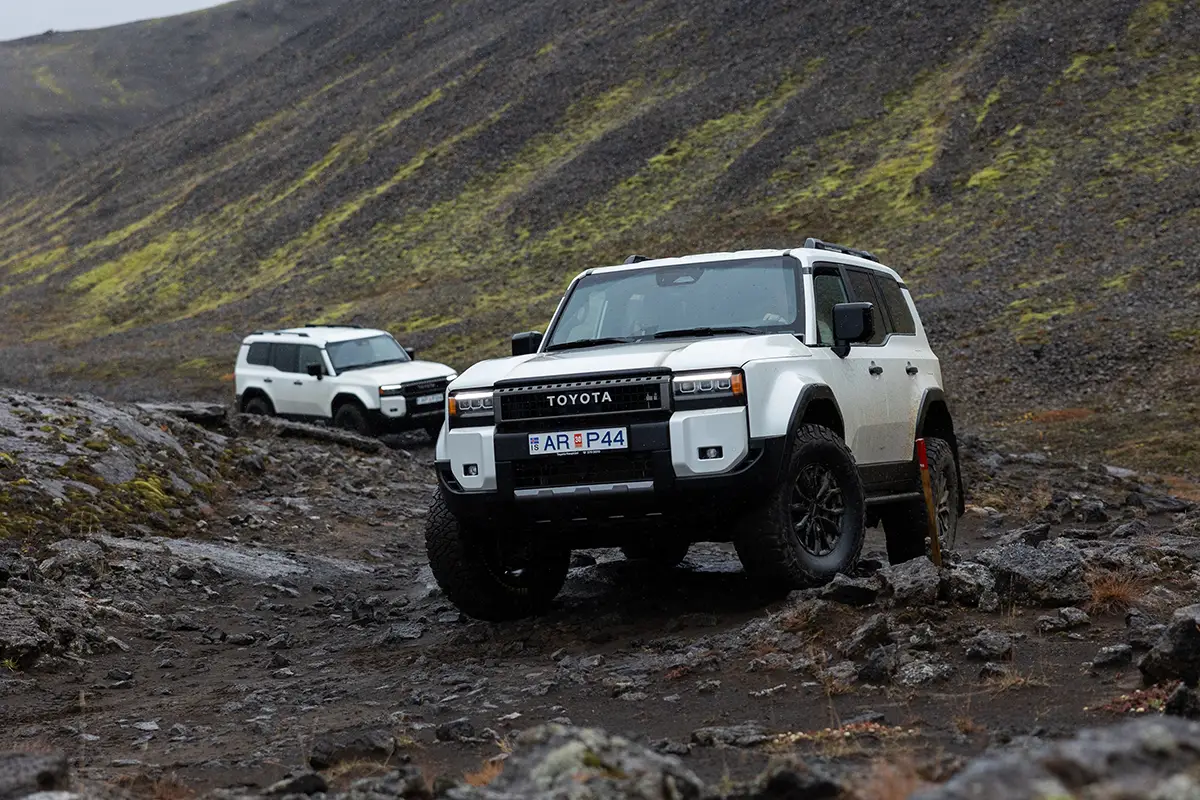 Weisser Toyota Land Cruiser mit 35-Zoll-Bereifung erklimmt eine felsige Geröllpiste im isländischen Hochland