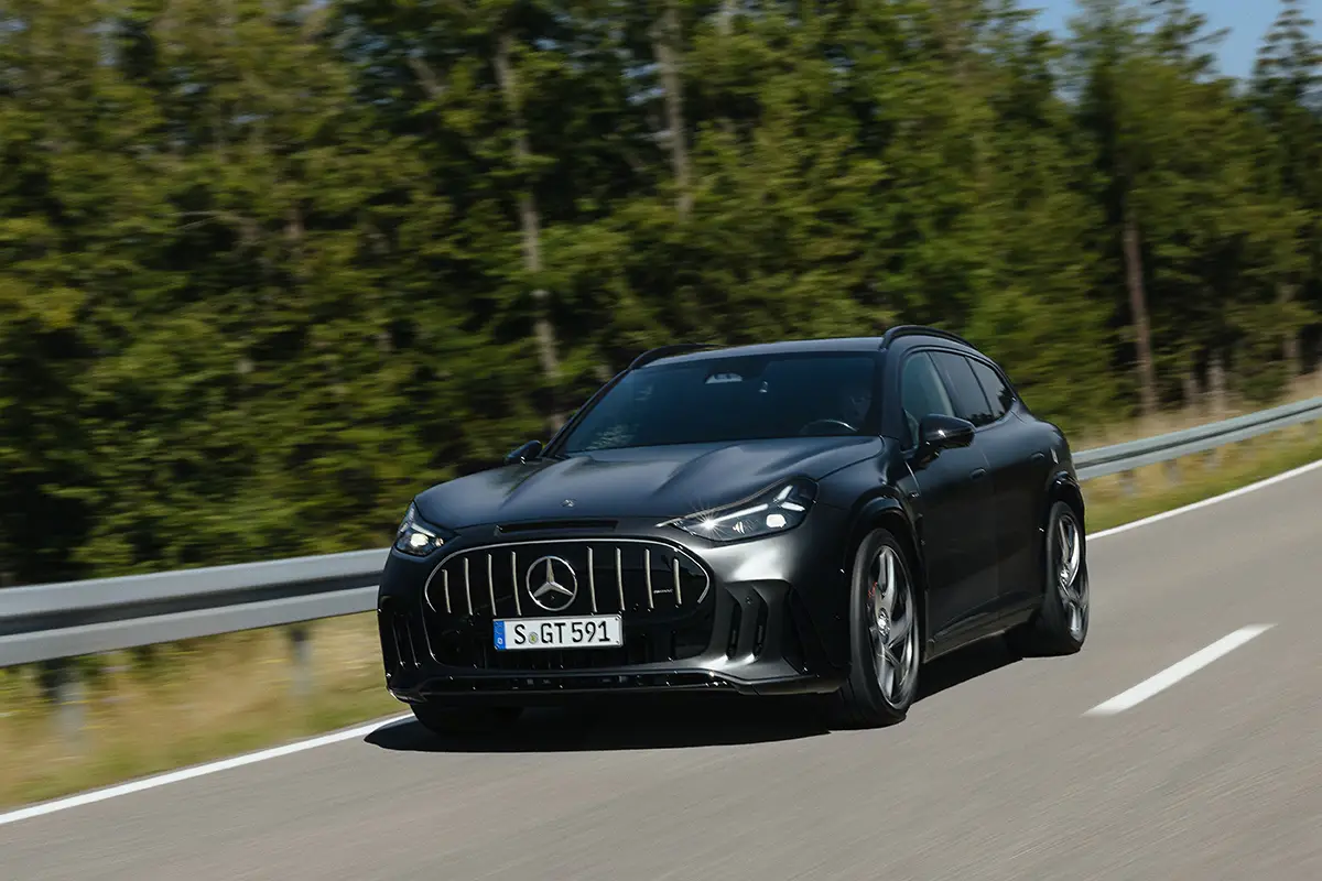 Dunkelgraues Mercedes-AMG GT SUV in Frontalansicht auf einer kurvigen Landstrasse vor grünem Wald