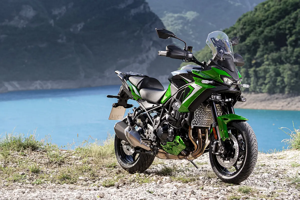 Grün-schwarze Kawasaki Versys 900 auf Schotterweg vor einem idyllischen Gebirgssee