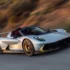Silberner Aston Martin Valhalla Spider in dynamischer Kurvenfahrt mit offenem Verdeck auf einer Bergstrasse