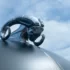 Detailaufnahme der verchromten Dodge Widder Kühlerfigur mit geschwungenen Hörnern auf einer mattschwarzen Oldtimer-Motorhaube gegen blauen Himmel