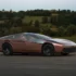 Flache Keilform des Giugiaro Peralta D mit glänzender Kupferkarosserie und verspiegelter Glashaube auf einer Landstrasse