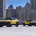 Gelber GMC Hummer EV SUV und gelber Pickup nebeneinander auf einem Plateau vor einer städtischen Wolkenkratzer-Skyline