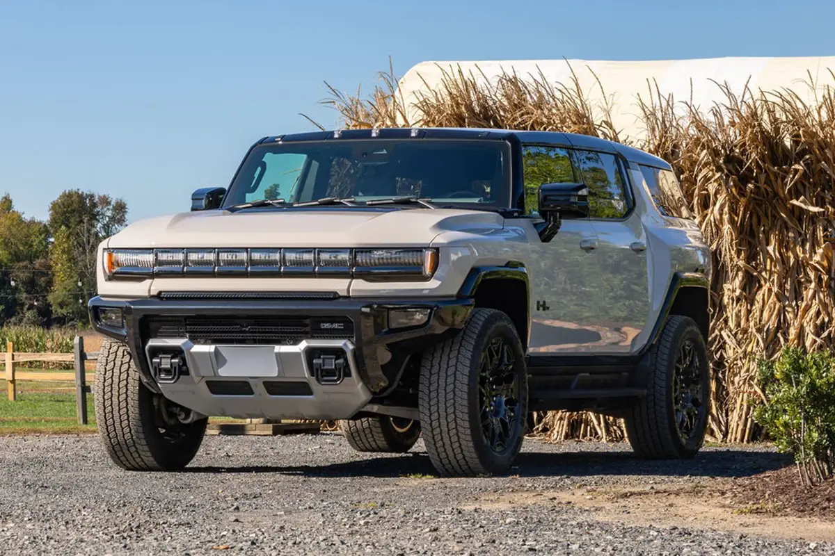 Frontansicht eines weissen GMC Hummer EV SUV geparkt auf einem Schotterplatz vor einer ländlichen Farmkulisse