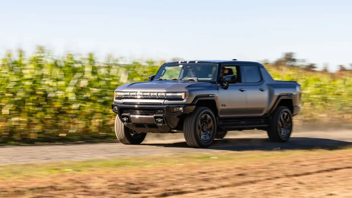 Dunkler GMC Hummer EV Pickup in Fahrt auf einer Landstrasse vorbei an einem dichten Maisfeld im ländlichen New Jersey