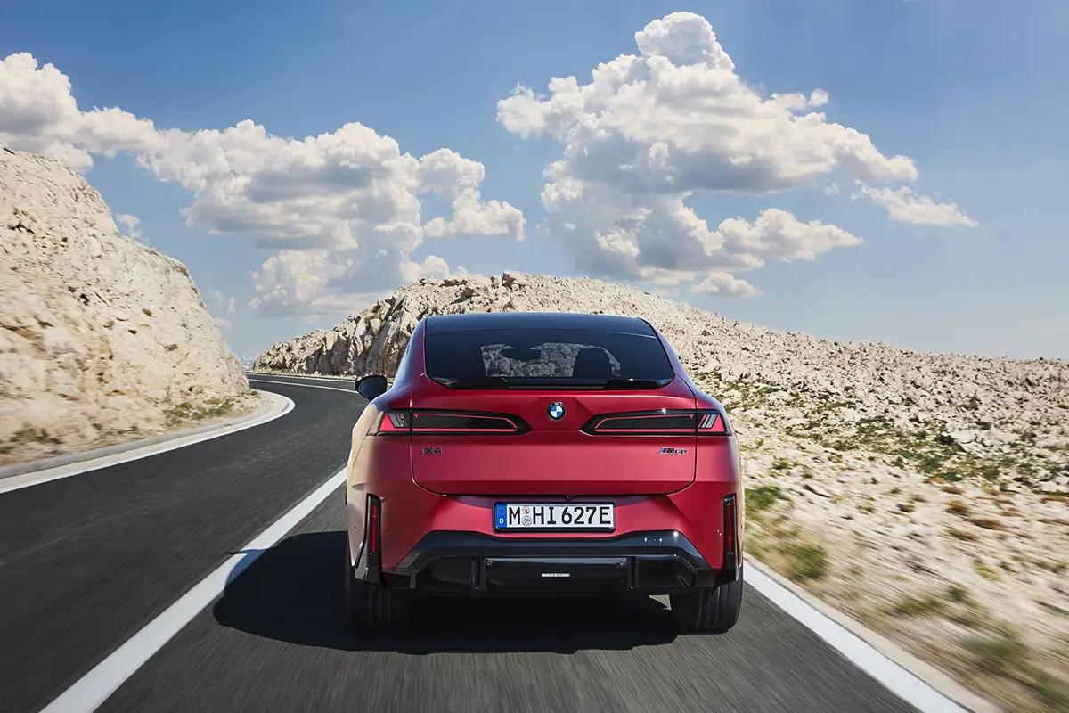 Heckansicht des BMW iX4 mit flacher Dachlinie, durchgehendem Leuchtenband und M-Sport-Heckdiffusor