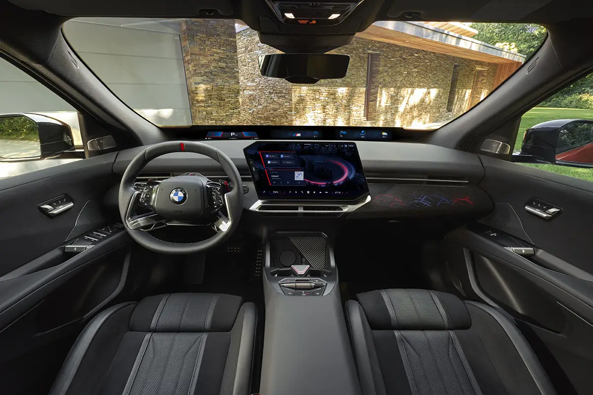 Cockpit des BMW iX4 mit 17,9-Zoll-Zentraldisplay und Panoramic-iDrive-Anzeigeleiste unter der Scheibe