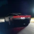 Breites Heck des neuen Tesla Roadster bei Nacht mit markantem roten LED-Leuchtband auf der Rennstrecke