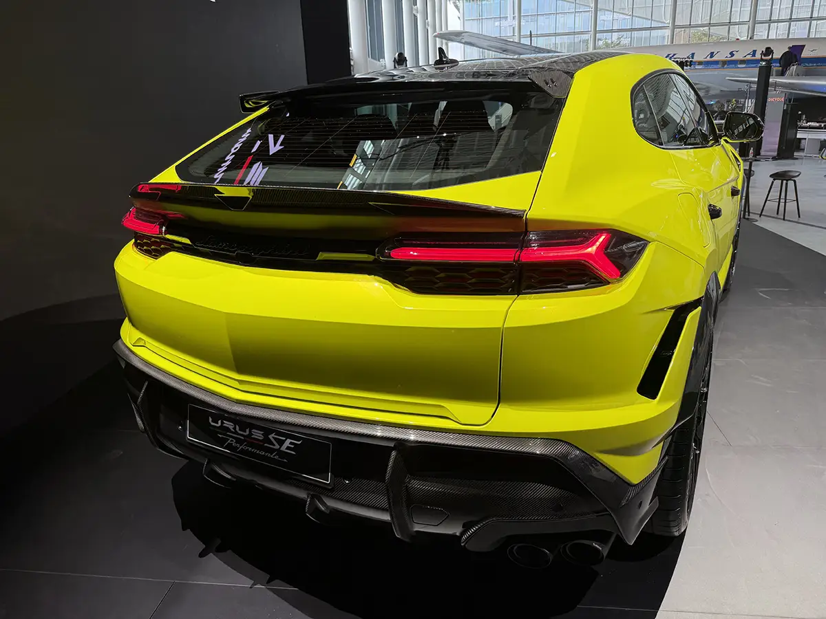 Heck des gelben Lamborghini Urus SE Performante mit LED-Leuchtband, Sportdiffusor und schwarzem Carbon-Spoiler