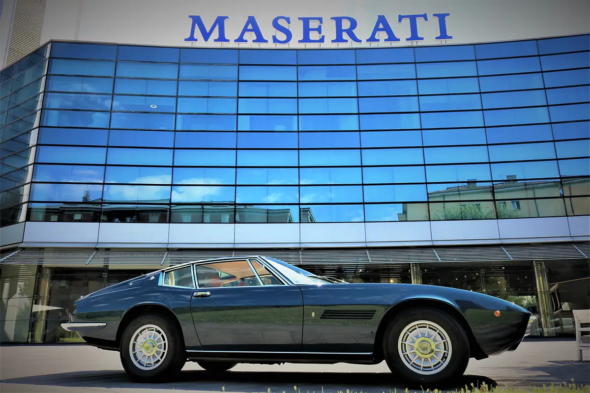 Das dunkelblaue Maserati Ghibli SS Coupé steht direkt vor dem modernen Maserati-Hauptgebäude in Modena. Foto: Maserati